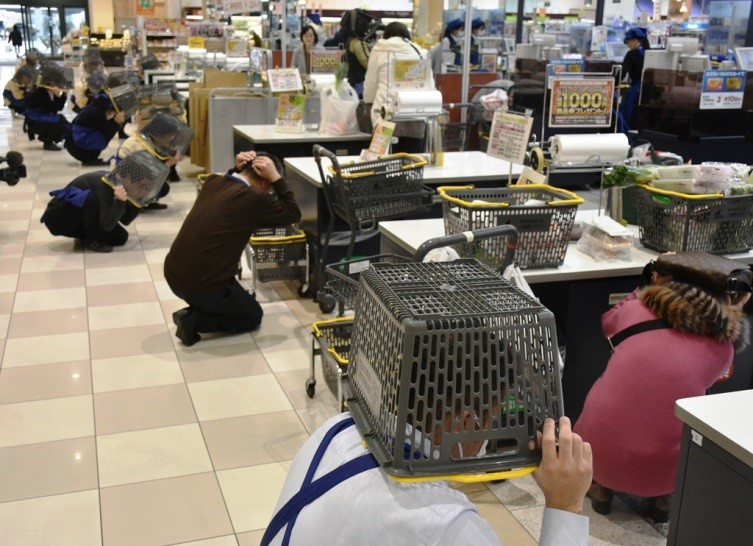 写真:商店で買い物かごをかぶって頭を守っている写真です。