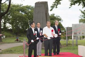 除幕に備える楫取素彦・星野長太郎・新井領一郎の子孫の方々と銅像建立委員会の会長・副会長(銅像の左側)