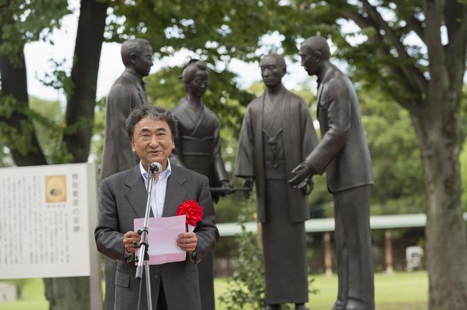 建立された銅像を前にスピーチを述べる制作者の三谷氏