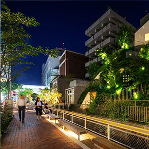 マンション街の夜景 光り輝くオブジェが飾られており通行人が眺めている