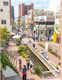 日中の街中の写真 走り回るこどもを中心に大勢でにぎわっている