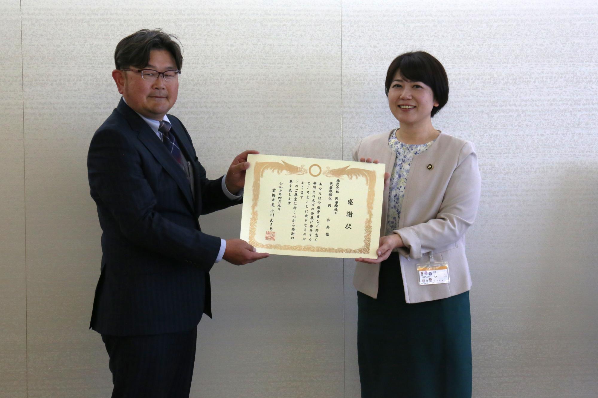 感謝状を手に持つ市長と岡運輸代表