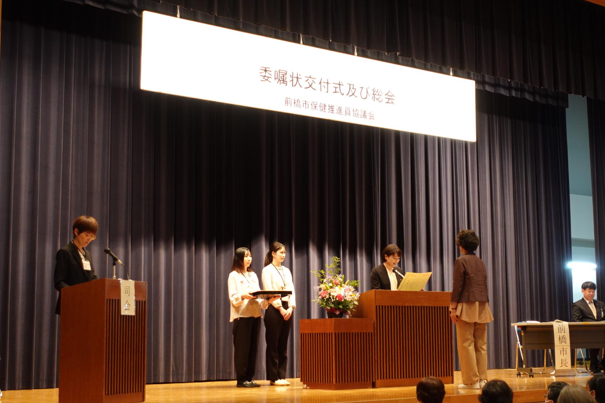 壇上で委嘱状を手にする市長