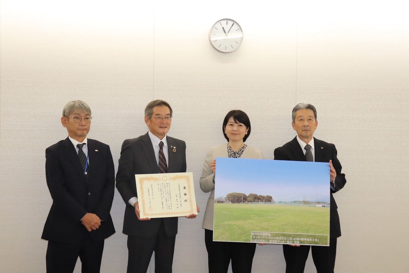 寄贈されたグランドのパネルを持つ小川市長と群馬県サッカー協会の関係者