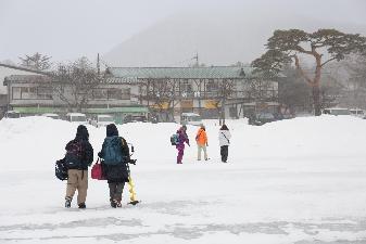 吹雪の中で大沼の上を歩くワカモノ記者たち