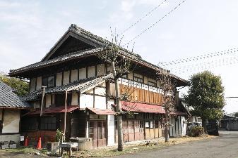 青空の下、旧本間酒造の店舗の外観写真