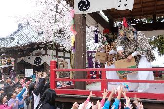 舞を行う台から投げ渡されるお菓子を目当てに手を伸ばす子どもたち