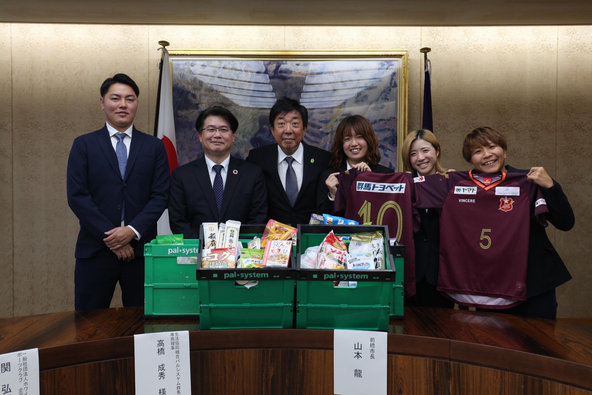 寄附された食品を前に集合写真を撮影