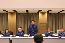 平成30年度総合防災訓練で、災害対策本部訓練中の写真です。紺色の防災服を着た市長をはじめ、副市長や教育長など、多くの職員が会議をしています。