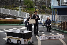 中央児童遊園への豆自動車贈与式の写真です。豆自動車は、白地にゴールドの線が入っている日本中央バスがモチーフです。