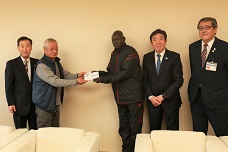 環境美化委員からの寄附を受け取る南スーダン選手団のジョセフコーチと市長の写真