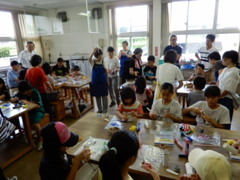 班ごとにテーブルに向かいリサイクル工作に集中する子供たち