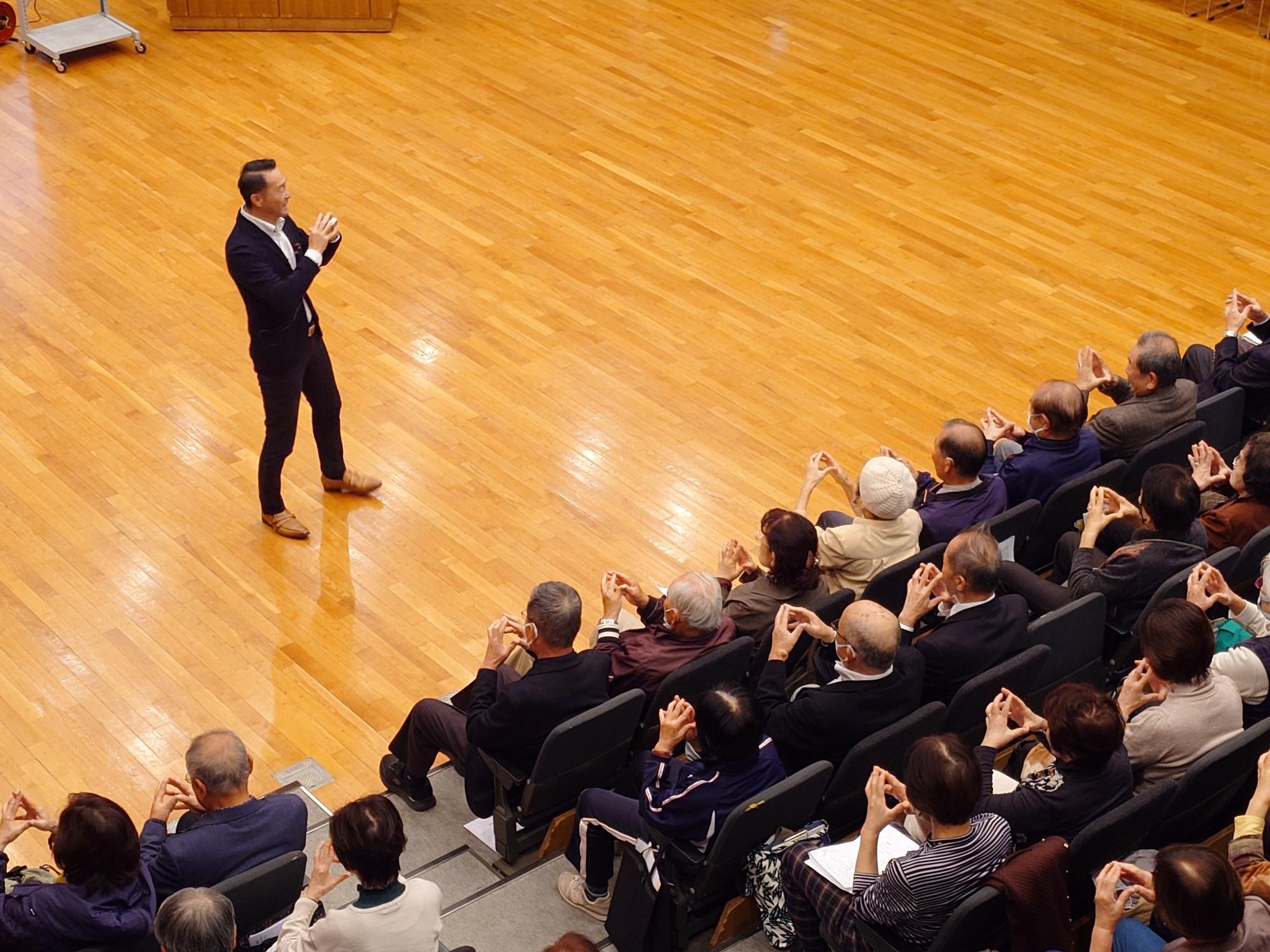 講師と一緒に指体操をする参加者