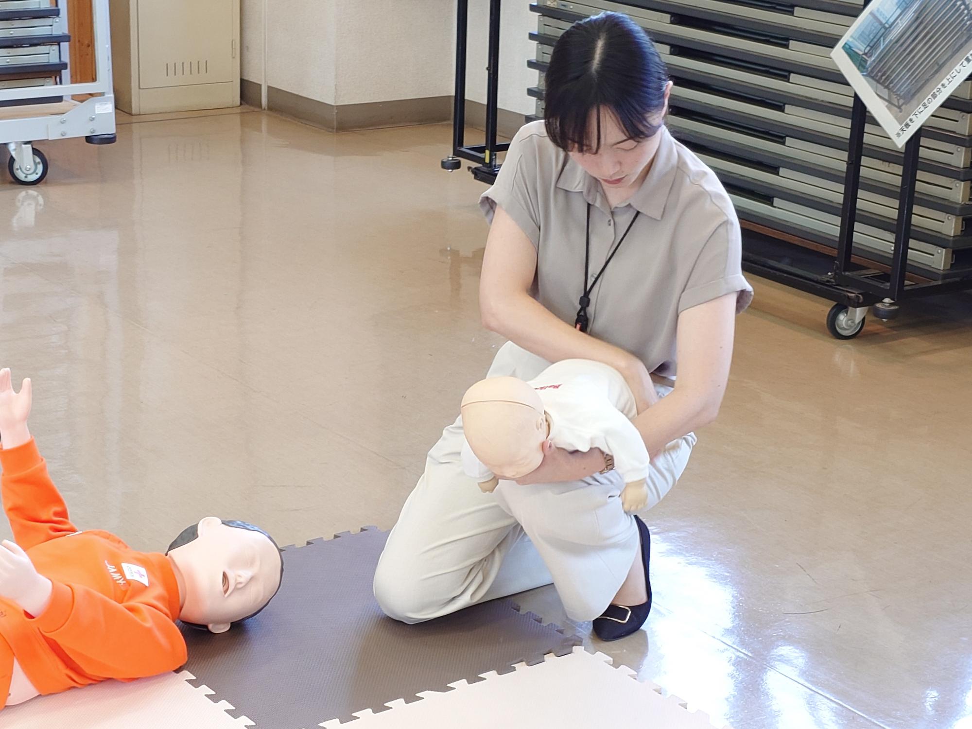 乳児人形で異物除去の方法を体験する参加者