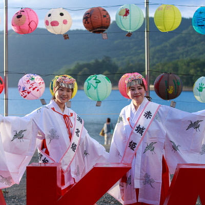 ローズクイーンが巫女の姿でAKAGIボードの前に立つ写真