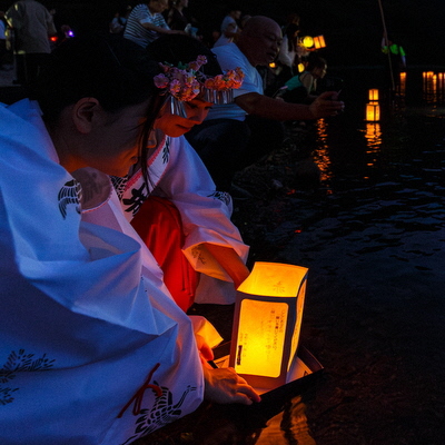 水辺で灯ろうを流している写真