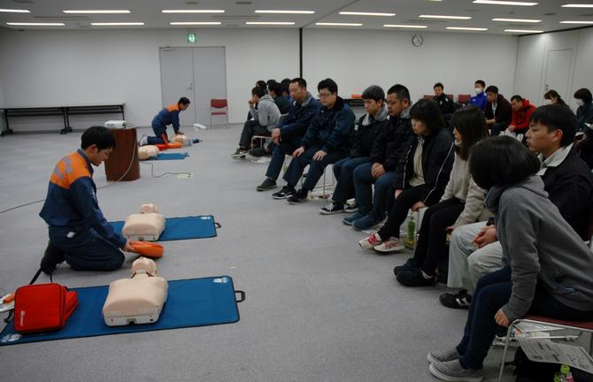 普通救命講習会にて、参加者が心肺蘇生法の説明を受けている写真
